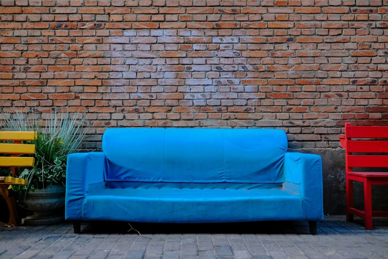 A bright blue sofa against a brick wall