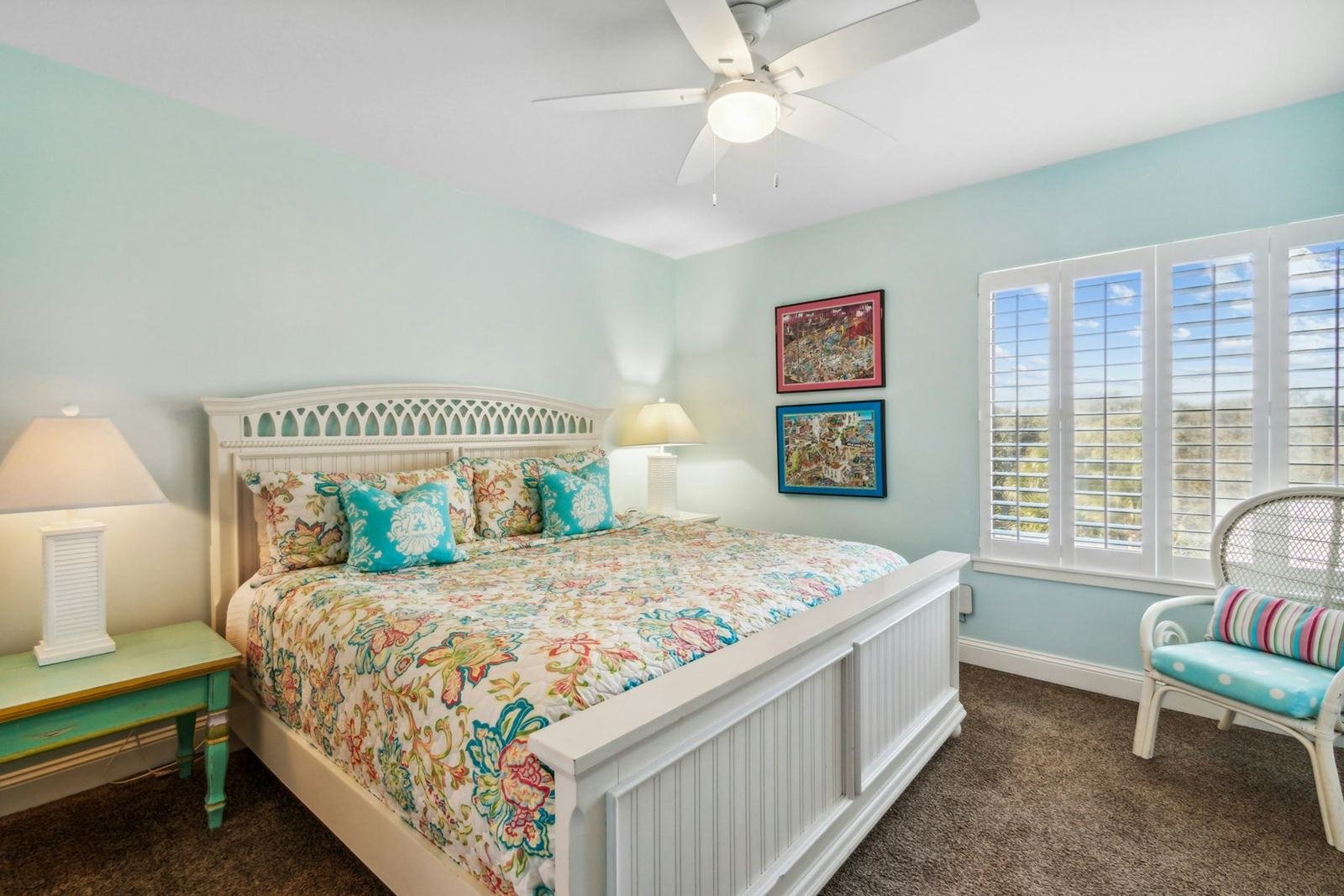 A bedroom with pale blue walls, white trim and plantation shutters