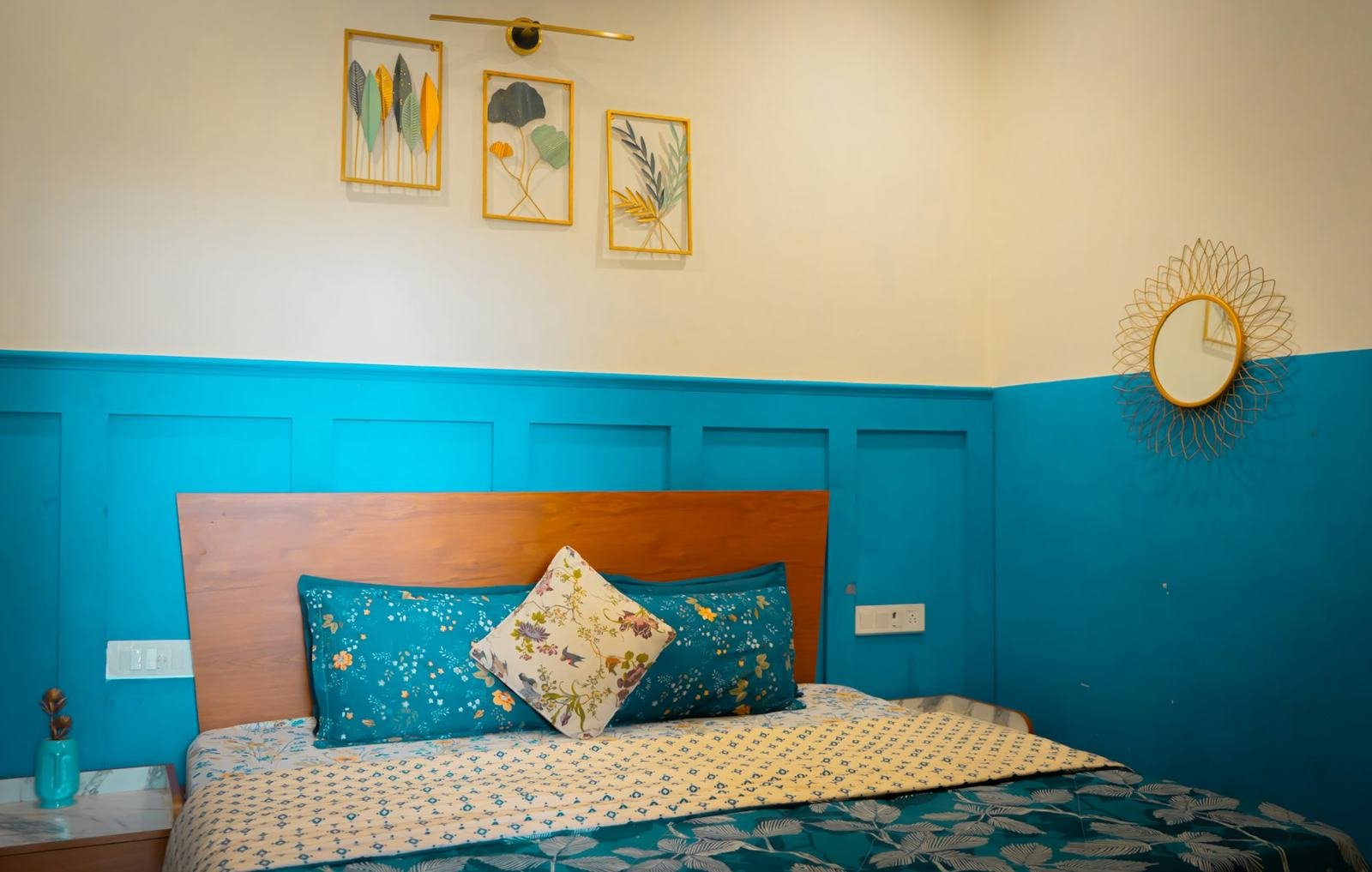 A bedroom with deep teal paneling below a cream wall